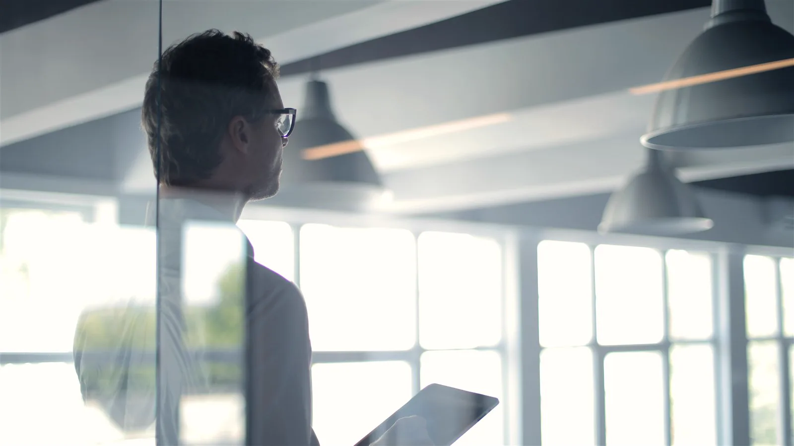 Businessman holding a tablet in a modern glass office
