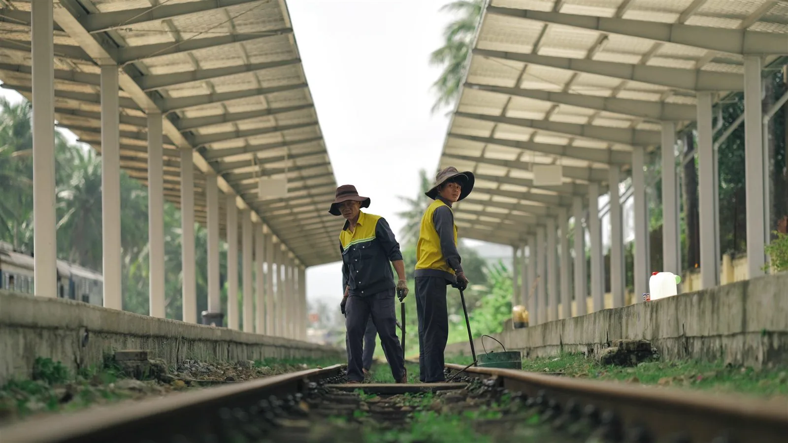 Track workers inspecting railway rails and sleepers at a station platform