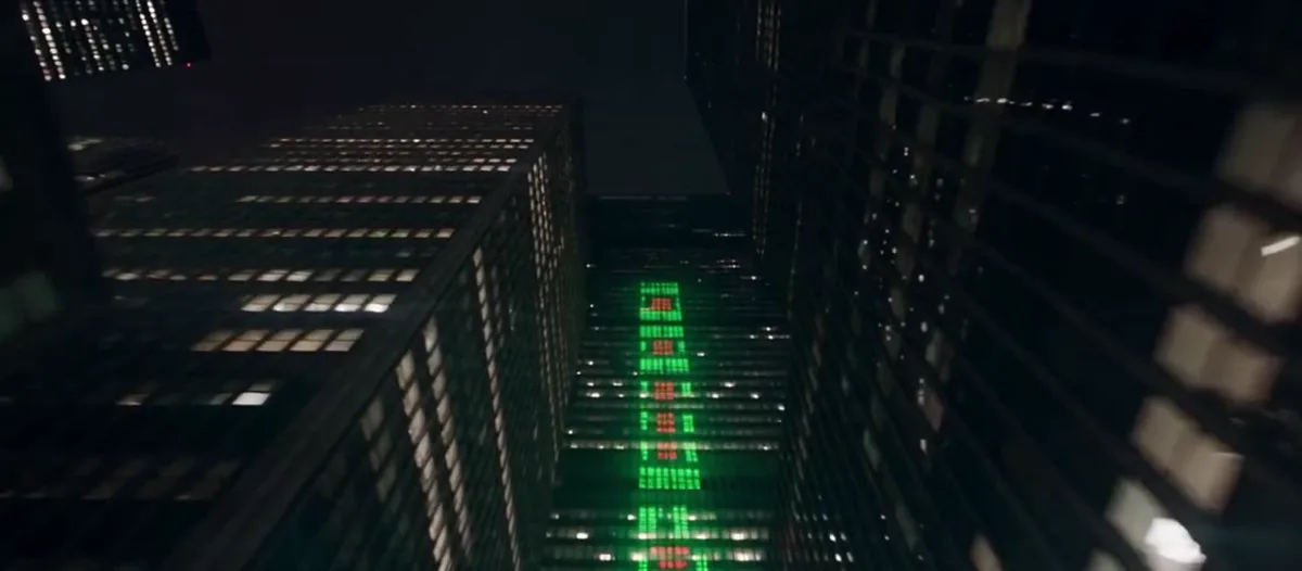 Looking up between night-time office towers, with a green and red market ticker running down one facade